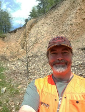 Presenting male with brown hat and orange vewst