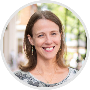 smiling  brown haired woman in grey pattern top 